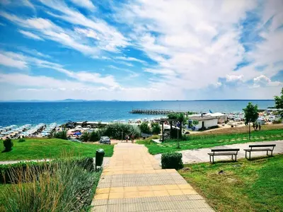 a walkway with benches and a view of the ocean at Бутикови апартаменти Емона in Ravda
