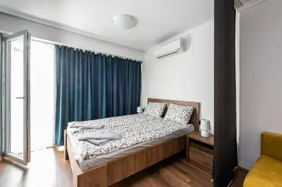 a bedroom with a bed with a blue curtain at МЯСТОТО in Burgas City