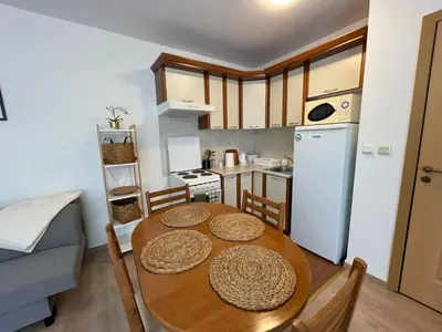 a kitchen with a wooden table with chairs and a refrigerator at Privilege Fort Beach - Prestige Sea Viev Apartments in Elenite