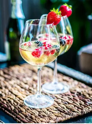 two glasses of wine and a strawberry on a table at Hotel AVENUE in Ravda