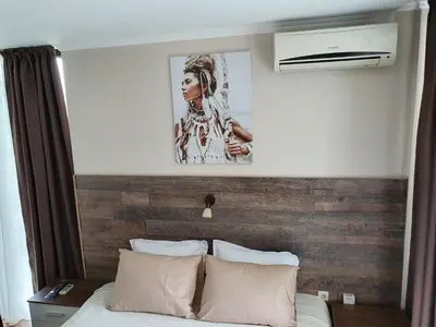 a bedroom with a bed with a wooden accent wall at Апартамент За Гости ,,1В-15