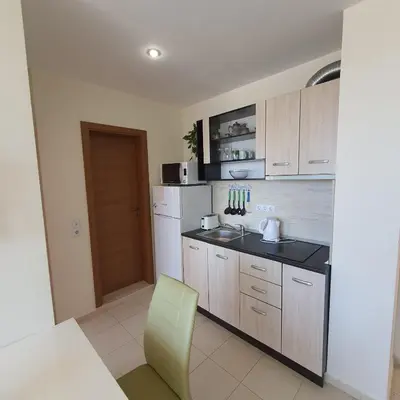 a kitchen with wooden cabinets and a yellow chair at Holiday Fort Golf Club - Premium Apartments in Sunny Beach