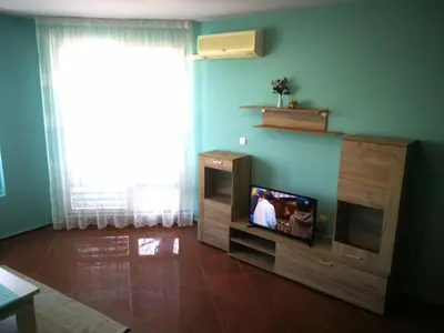 a living room with a television in a wooden entertainment center at Апартамент за гости Соня Guest Apartment Sonya in Nesebar