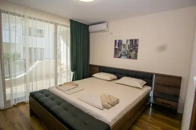 a bedroom with a bed and a large window at Guest apartments STELA in Tsarevo
