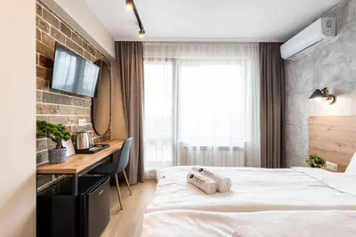 a hotel room with a bed and a desk at Хотел Камъните in Burgas City