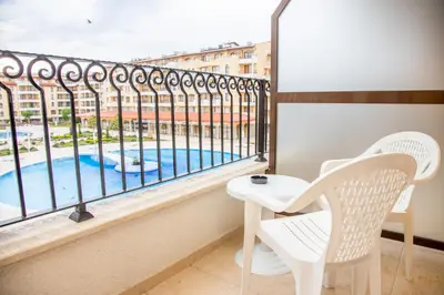 a balcony with a table and chairs and a pool at Sunny apartment in a complex with a POOL and GYM by Flаt Manаger in Sunny Beach