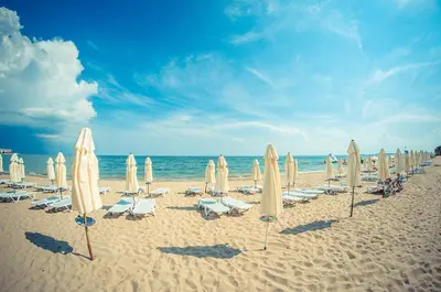 a bunch of umbrellas and chairs on a beach at PANORAMA MARINA FORT BEACH & GRAND RESORT - Premium Apartments Sea Viev in Sveti Vlas