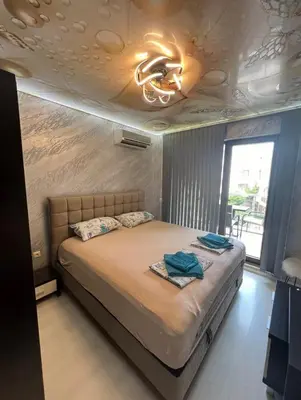 a bedroom with a bed and a ceiling with a chandelier at Менада Хоризонт Апартаменти in Sozopol