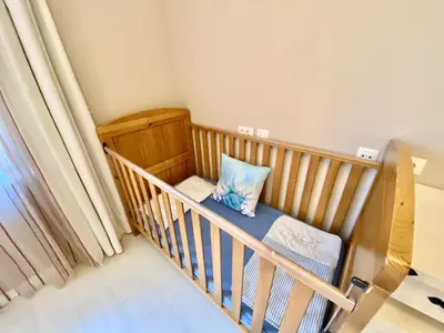 a crib with a blue pillow in a room at Santa Marina 2-bedroom apt. w/ Sea View + Terrace in Sozopol