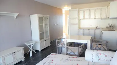 a kitchen with white cabinets and a table in a room at Captain's Island Deluxe in Chernomorets