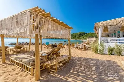 a beach with chairs and umbrellas on the sand at Captain's Island Deluxe in Chernomorets