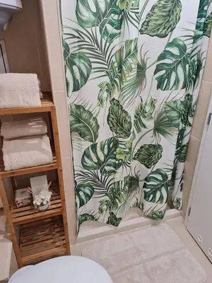 a bathroom with a shower curtain with green leaves at Little Treasure by the Sea in Pomorie