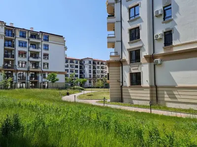 a tall building with a grass field next to it at Little Treasure by the Sea in Pomorie