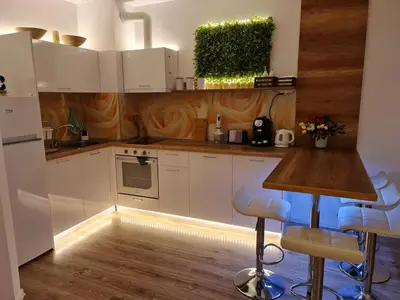 a kitchen with white cabinets and blue bar stools at Little Treasure by the Sea in Pomorie