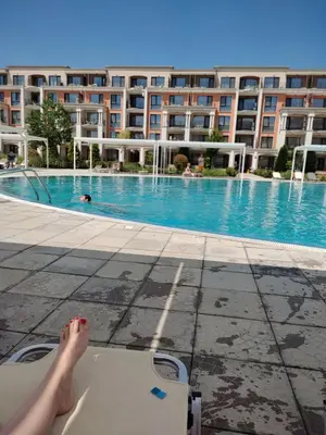 a person laying on a chair in front of a swimming pool at Prestige Fort Beach Private Apartment-Studio 46 in Sveti Vlas