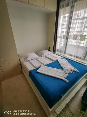 a bedroom with a bed with blue sheets and a window at Luxury Apartments Alix in Burgas City