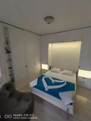 a bedroom with a bed with blue sheets and a chair at Luxury Apartments Alix in Burgas City
