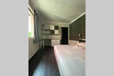 a bedroom with a bed and a brick wall at Cute Little House with a White Picket Fence in Burgas City