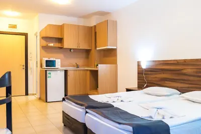 a bedroom with a large bed and a kitchen at Admiral Plaza Premium Apartments in Sunny Beach