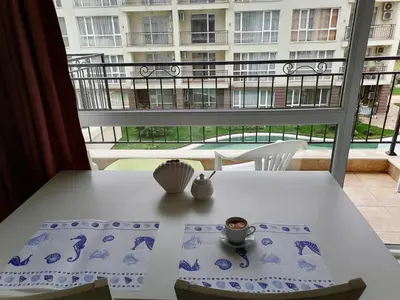 a white table with a cup of coffee on a balcony at Cozy studio with Pool in Sunny Beach in Sunny Beach
