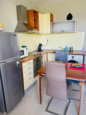 a kitchen with a refrigerator and a table with a chair at Апартамент Морски Изглед in Burgas City