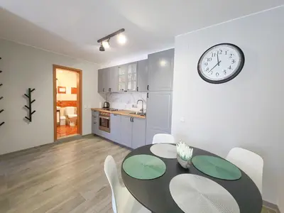 a dining room with a table and a clock on the wall at Prestige Fort Aparthotel - Private apartment-BSR in Sveti Vlas
