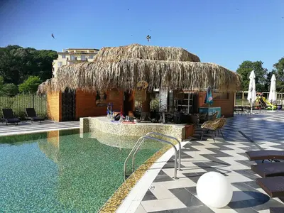 a resort with a swimming pool and a straw hut at Donchevi Apartments in Primorsko