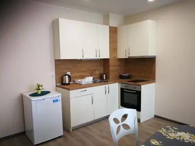 a small kitchen with white cabinets and a white chair at Donchevi Apartments in Primorsko