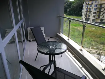 a table and chairs on a balcony with a window at Donchevi Apartments in Primorsko