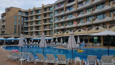 a hotel with chairs and umbrellas next to a pool at Grenada Apartaments in Sunny Beach