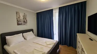 a bedroom with a bed and a window with blue curtains at Apartment on the beach Ravda in Ravda