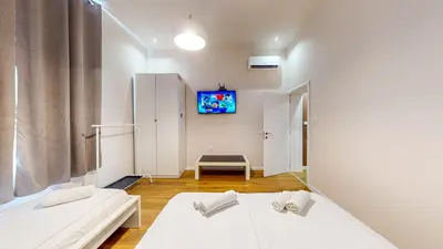 a room with two beds and a tv on the wall at Markoni 1 in Burgas City