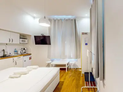 a white room with a bed and a kitchen at Markoni 2 in Burgas City