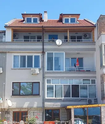 an apartment building with a balcony with a roof at Стаи за гости WEST in Pomorie