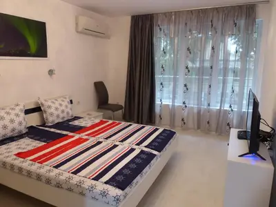 a bedroom with a bed and a desk with a television at Apartament HOLIDAY in Burgas City