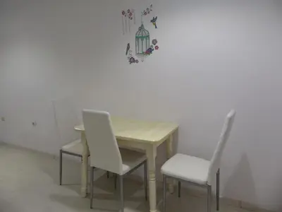 a wooden table with two white chairs and a table and a wall at Apartament HOLIDAY in Burgas City