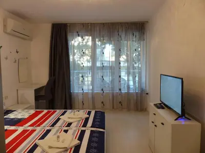 a bedroom with a bed and a tv and a window at Apartament HOLIDAY in Burgas City