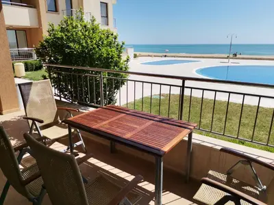 a balcony with a table and chairs and a swimming pool at Апартамент Б003 в Обзор Бийч Резорт- море пред прозореца, плаж пред вратата !!! in Obzor