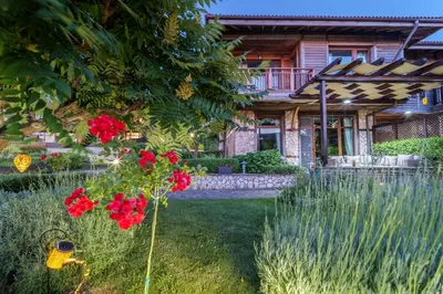 a garden with red flowers in front of a house at Luxury 3-bedroom villa in Sozopolis with sea view in Sozopol