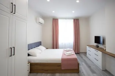 a small bedroom with a bed and a television at Апартамент за гости Стела in Burgas City