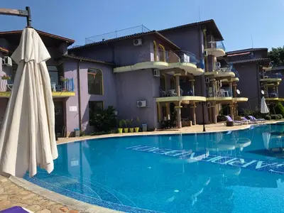 a swimming pool with an umbrella and a hotel at Apartment Black Sea Shark in Chernomorets