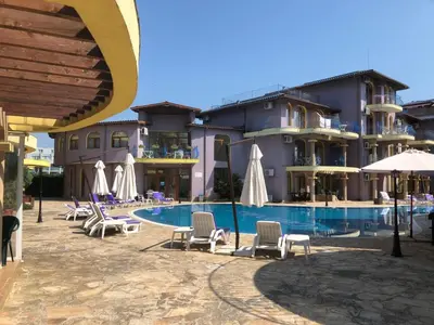 a hotel with chairs and umbrellas next to a pool at Apartment Black Sea Shark in Chernomorets