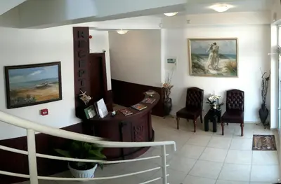 a waiting room with chairs and paintings on the wall at Семеен Хотел 