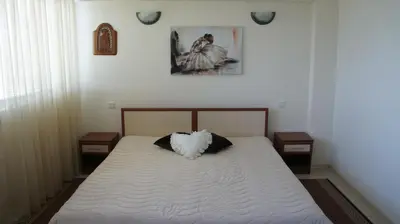 a bedroom with a white bed with two night stands at Семеен Хотел 
