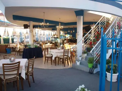 a restaurant with tables and chairs and a staircase at Семеен Хотел 
