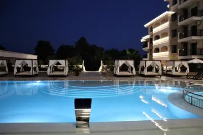 a large swimming pool with chairs and a building at night at Valencia Gardens Luxury Studios in Nesebar