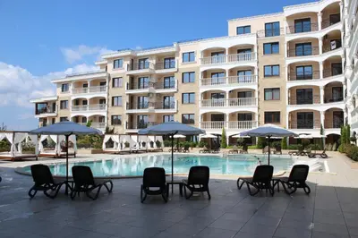 a hotel with chairs and umbrellas next to a swimming pool at Valencia Gardens Luxury Studios in Nesebar