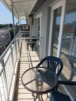 a porch with a table and chairs on a balcony at Къща за гости WEST in Sunny Beach
