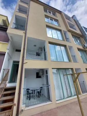 an apartment building with glass windows and a table at Къща за гости WEST in Sunny Beach