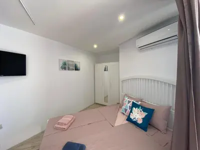 a white room with a bed and a tv at PARADISO 'В' 109 Large Cozy Studio NESEBAR in Nesebar